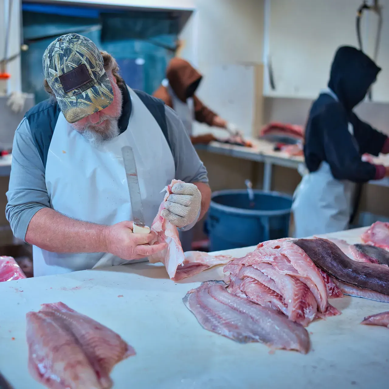 A Water Street cutter trimming a fillet by hand beside a table of finished fillets